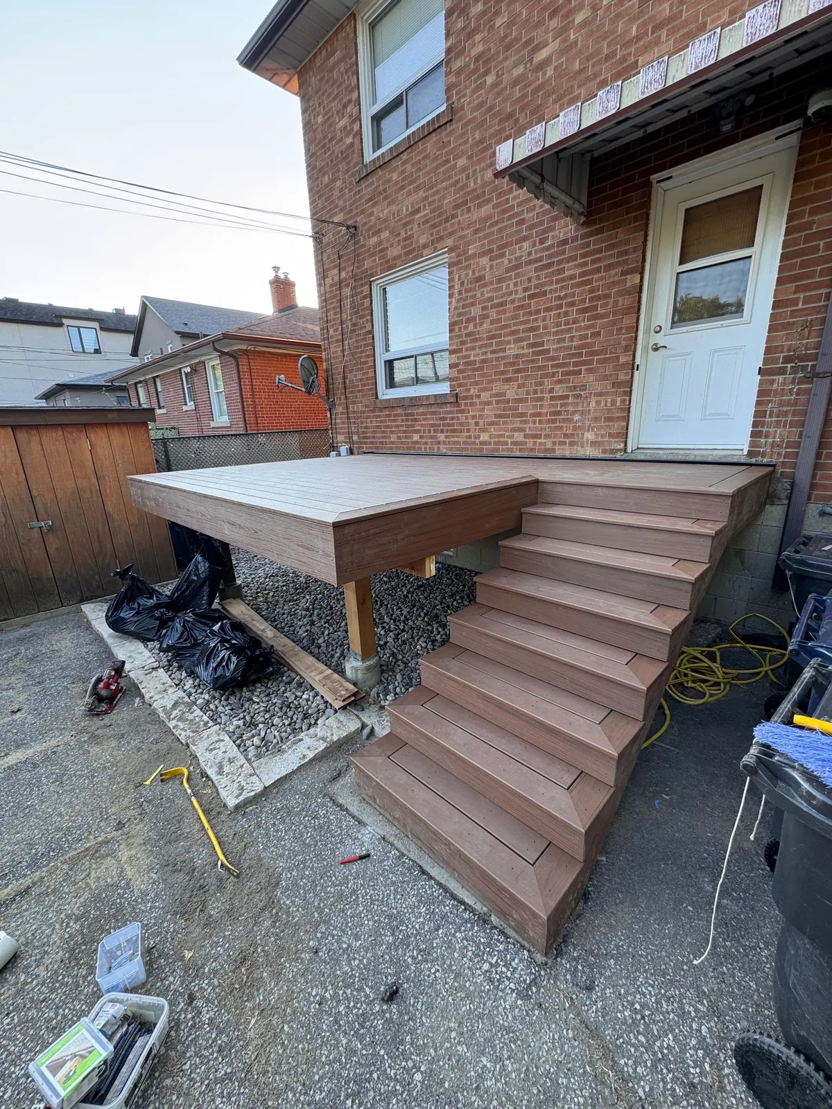 Low raised deck platform with wide steps at the back door of a brick house