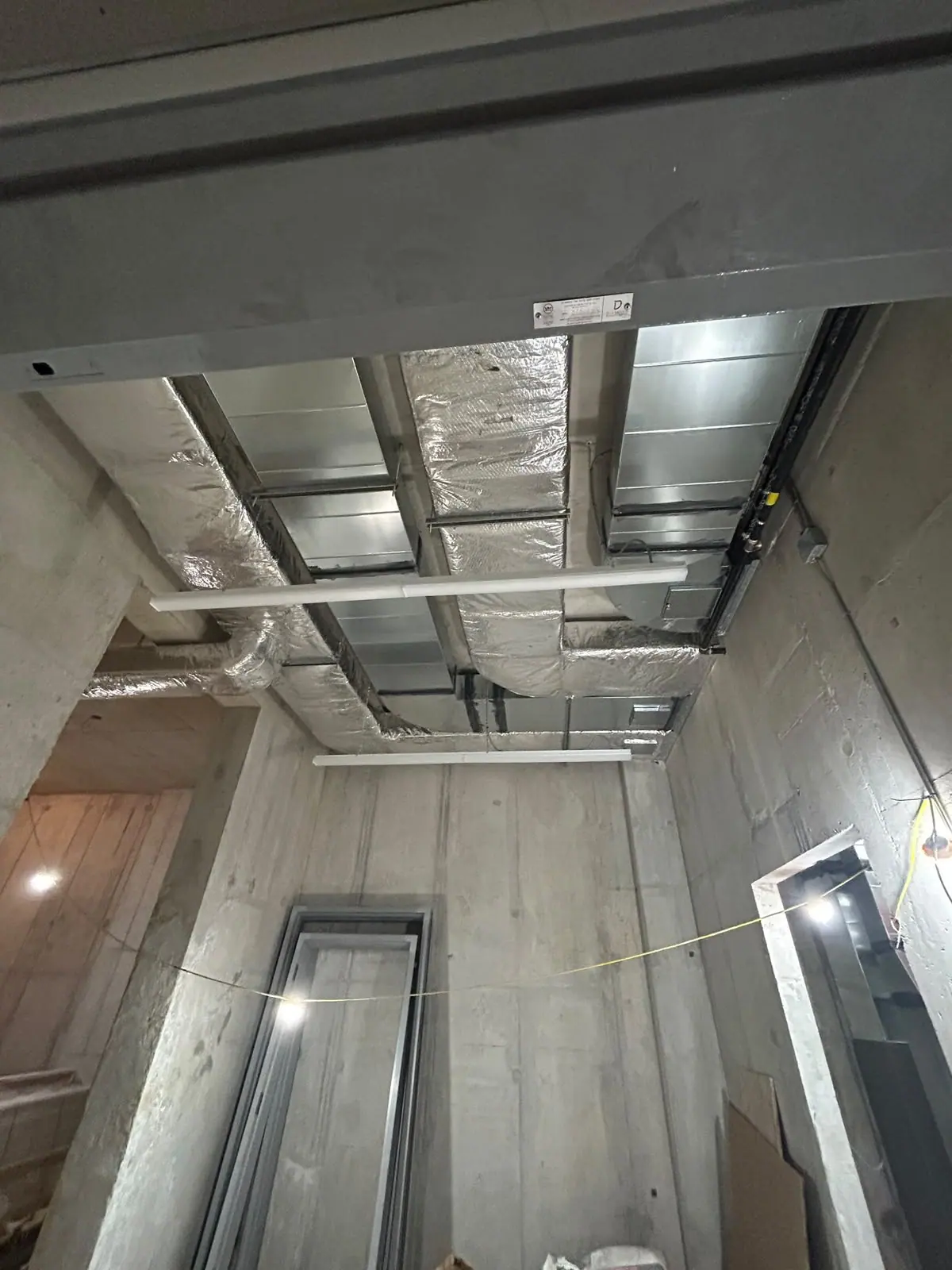 Exposed overhead ductwork and concrete walls during an interior build-out